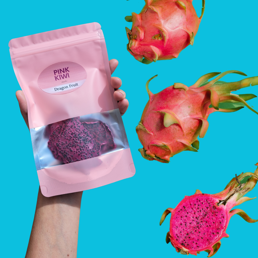 Hand holding Pink Kiwi dried dragon fruit snack pouch with fresh dragon fruits floating on a vibrant blue background, showcasing healthy exotic fruit snack branding.