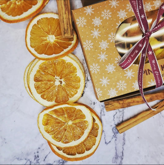 Festive Pink Kiwi Christmas gift box with dried orange slices and cinnamon sticks on a marble background — perfect for holiday gifting.