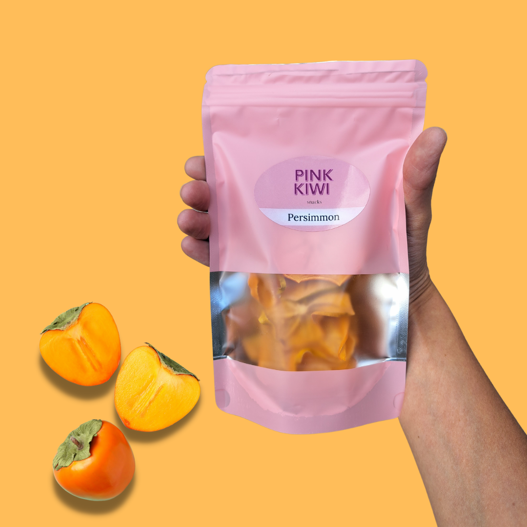 pink-kiwi-dried-persimmon-snack-handheld-orange-background