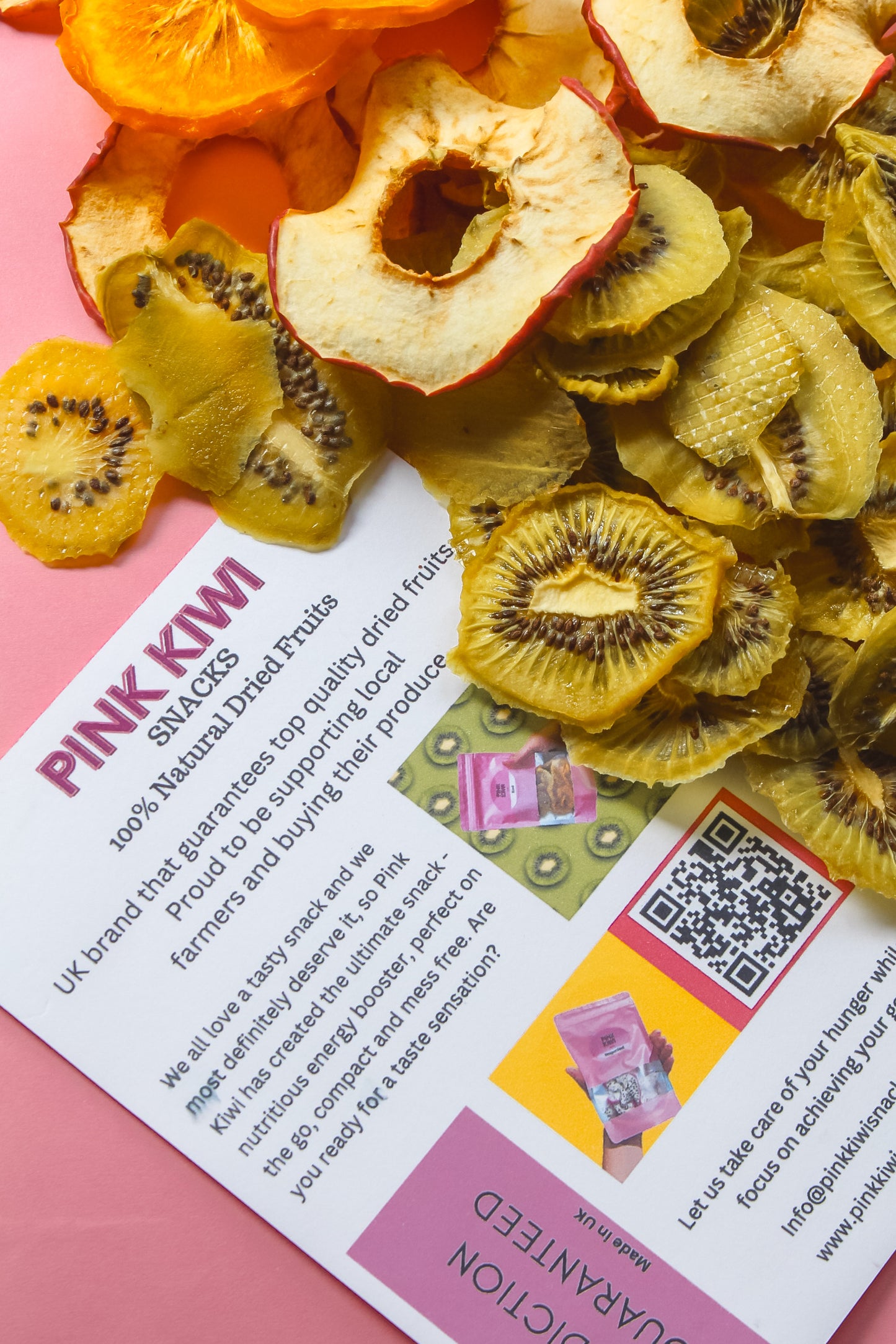 Pink Kiwi Snacks flyer with dried kiwi and apple slices on a pink surface, showcasing natural fruit chips.